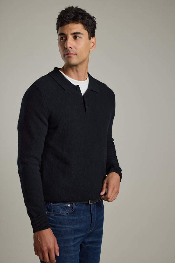 Man in Barkers Ainsley Woollen Long Sleeve Polo and jeans stands against a plain background.