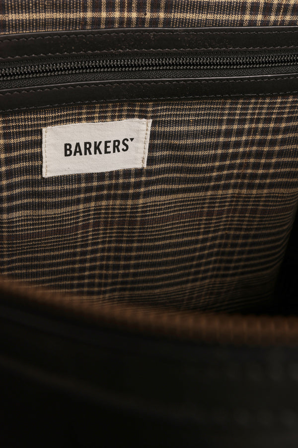 A close-up of the Costello Leather Weekender by Barkers shows its brown plaid fabric lining, a zippered pocket, and a white label marked "BARKERS.