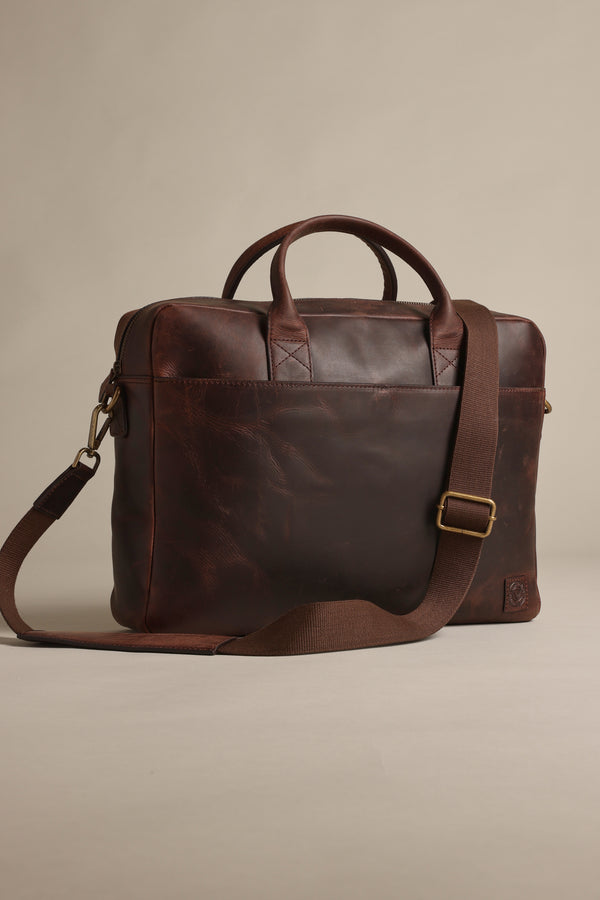 The Barkers Wilkinson Leather Laptop Bag, in dark brown with two handles and an adjustable shoulder strap, is ideal for commuters and is showcased against a neutral background.
