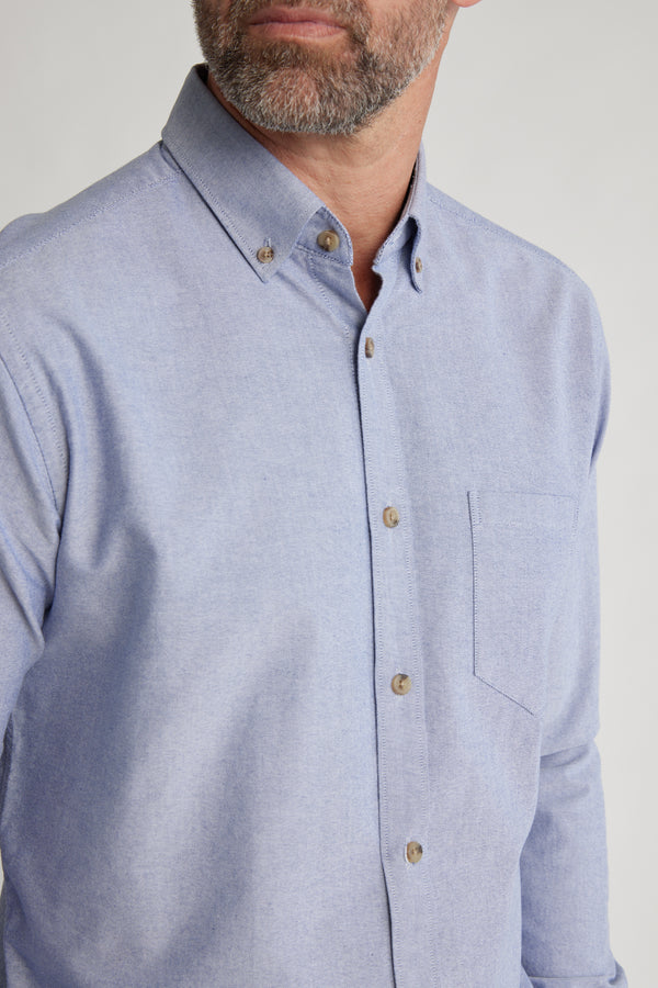 A man with a short beard wears the Barkers Thatcher Oxford Shirt—light blue, button-down collar, chest pocket, and made from responsibly sourced cotton—standing against a plain light background.