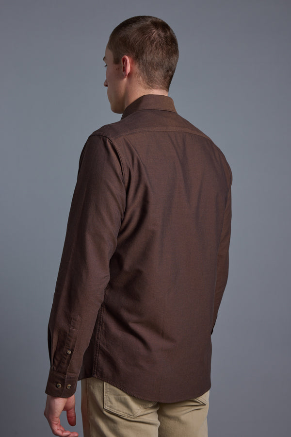 A man with short brown hair stands with his back to the camera, wearing the Barkers Thatcher Oxford Shirt in brown and light beige pants against a plain gray background.