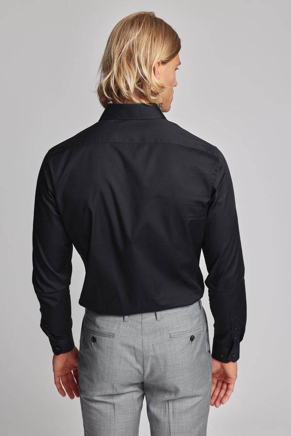 A man with shoulder-length blonde hair, wearing a Barkers Tribeca Reg Cuff Shirt and light gray dress pants, stands with his back to the camera.