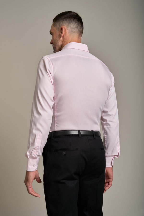 A man stands with his back to the camera, wearing a Barkers Tribeca Reg Cuff Shirt in light pink, tucked into black dress pants with a black belt, against a plain background.