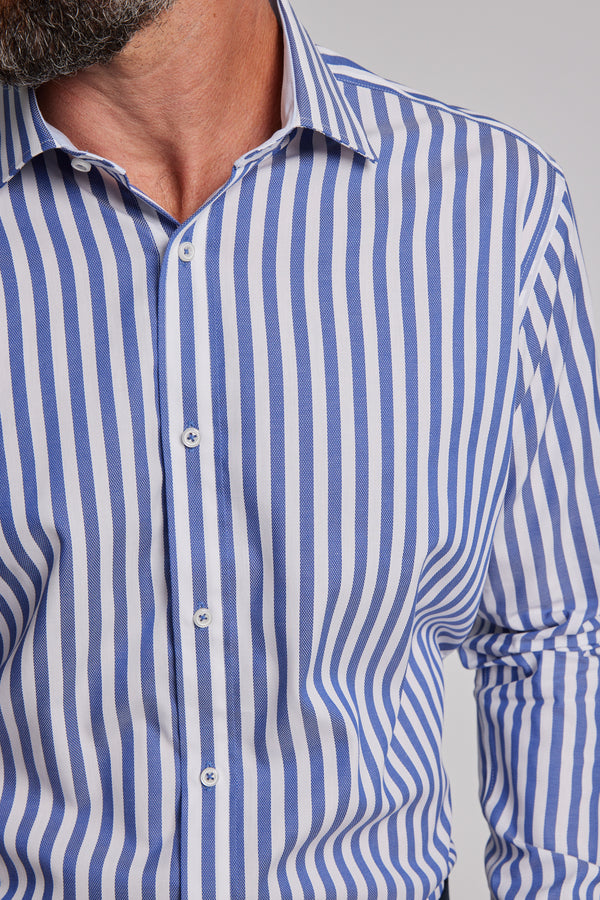 A man wears the Barkers Midway Shirt, a blue striped, tailored-fit business shirt with an open collar. The image shows his chest, arm, and part of his neck and beard.