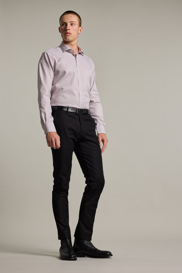 A man stands against a plain background, wearing the Barkers Marbury Check Business Shirt, black dress pants, a black belt, and black dress shoes. He looks off to the side with a neutral expression.