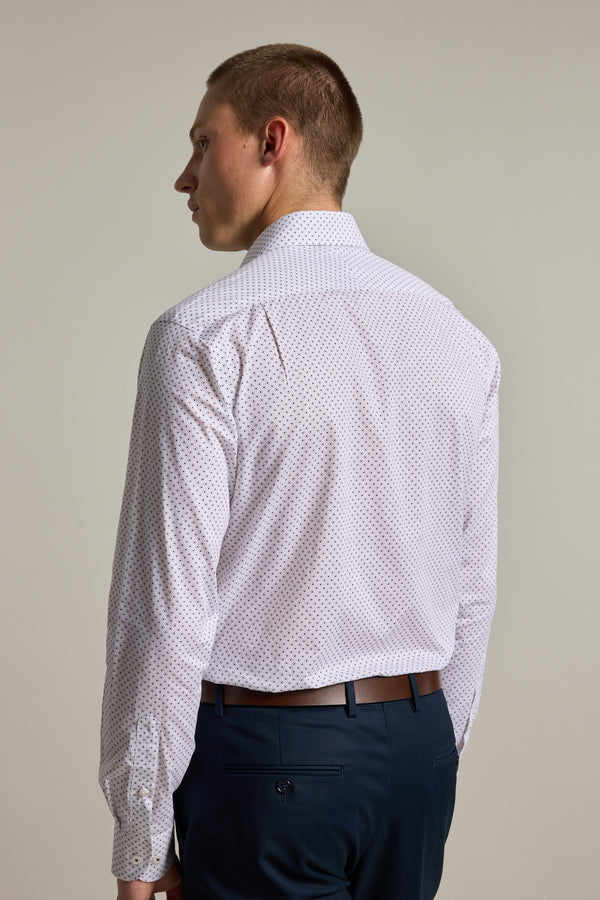 A man with short hair, dressed in the Barkers Foster Print Business Shirt and dark blue trousers, stands facing away from the camera against a plain light background.
