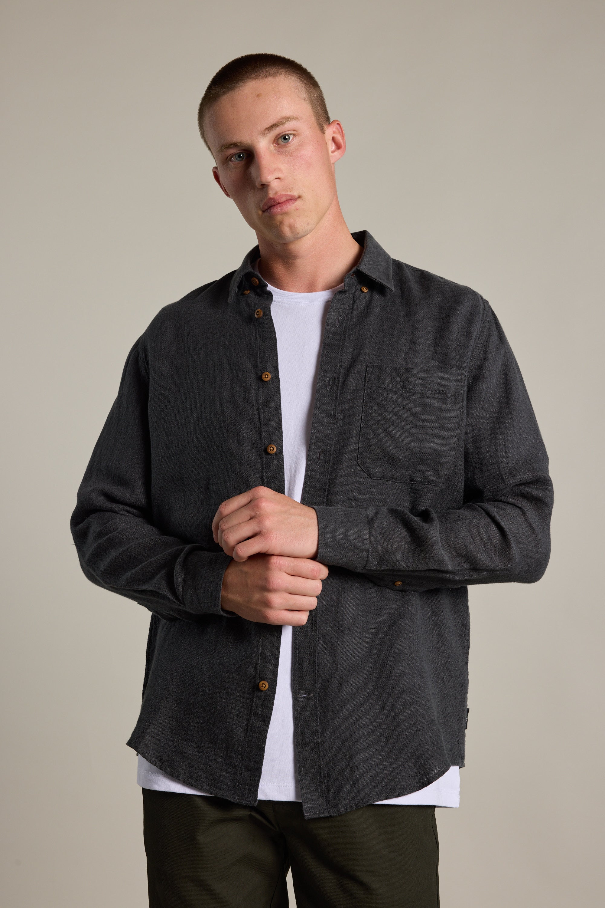 A person with short hair wears the Barkers Delano Linen Shirt in a classic fit over a white tee, standing against a plain background with hands loosely clasped and looking at the camera with a neutral expression.