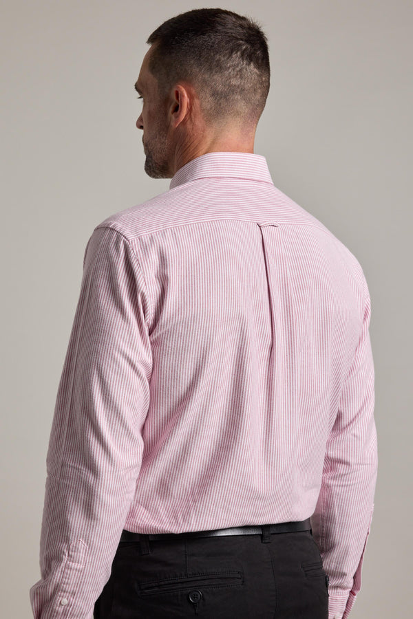 A man with short dark hair is seen from behind, dressed in a Barkers Maynard Oxford Stripe Shirt in light pink and white with black trousers, standing against a neutral background.