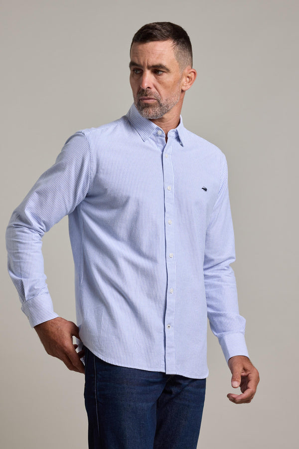 A man with short dark hair and a beard wears the Barkers Maynard Oxford Stripe Shirt and dark jeans, standing against a plain light background and looking to his left with a neutral expression.