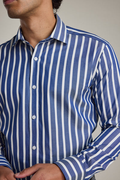 A person wears the Barkers Nandas Stripe Business Shirt, featuring blue and white vertical stripes, a tailored fit, and wrinkle-resistant fabric; one hand is near the waist and their face is partially out of frame.