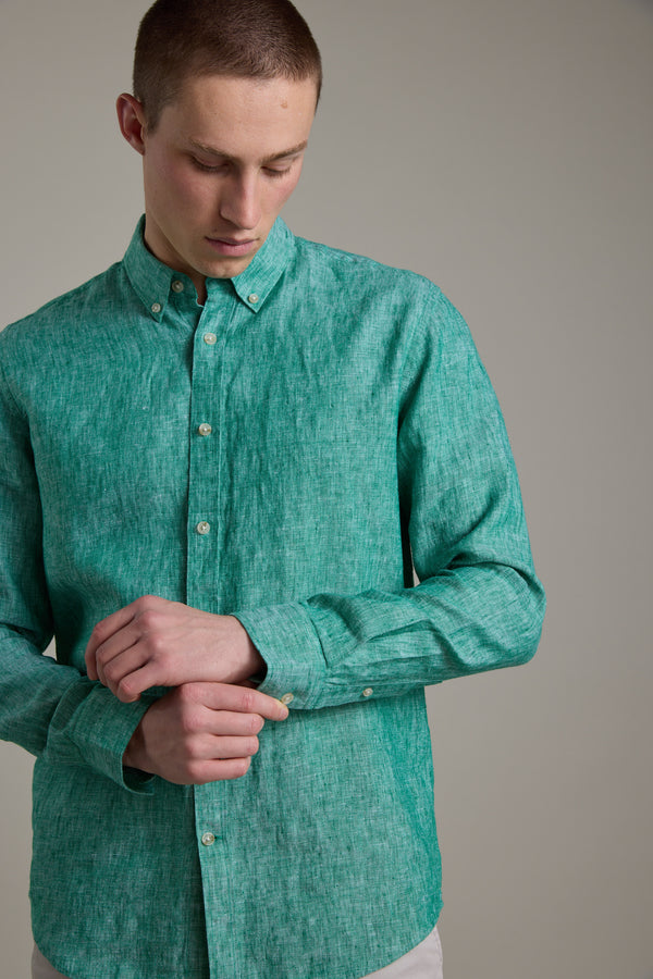 A person wearing the Barkers Dorset Linen Shirt in green, tailored fit, fastens a cuff button while standing against a plain, neutral background.