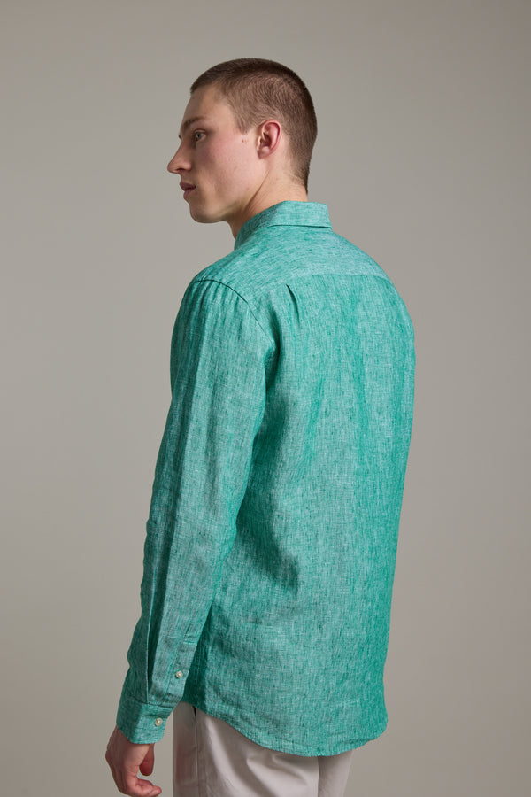 A young man with short hair models the Barkers Dorset Linen Shirt in light green, featuring a tailored fit, paired with light-colored pants, as he stands facing slightly away from the camera against a plain, neutral background.