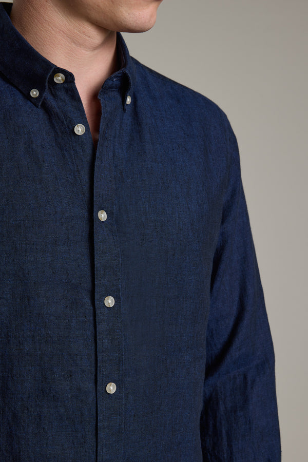 A person models the Barkers Dorset Linen Shirt in dark blue, featuring a tailored fit and button-down collar; their face is partially out of frame against a plain background.