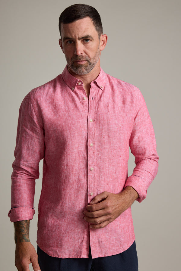 A man with short dark hair and a beard wears the Barkers Dorset Linen Shirt in pink, tailored fit with long sleeves rolled up, standing against a plain light background.