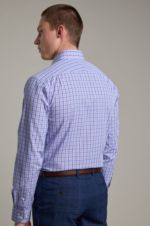 A man with short brown hair stands facing away, wearing the Barkers Denton Check Business Shirt in light purple plaid and blue plaid pants against a plain light background.