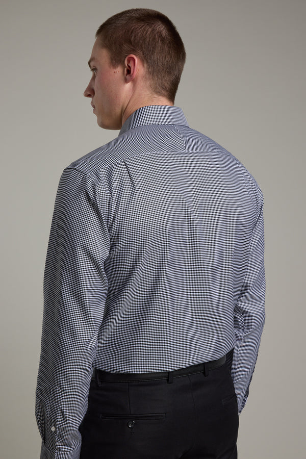 A man models the Barkers Mitchel Check Business Shirt and black trousers, standing with his back to the camera and head turned left, set against a plain background.