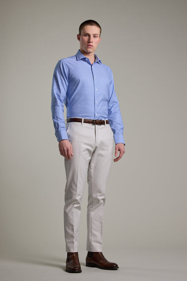 A man stands against a plain background wearing the Barkers Mitchel Check Business Shirt, light beige pants, a brown belt, and brown dress shoes. He looks straight ahead with a neutral expression. The shirt features a tailored fit for a sharp look.