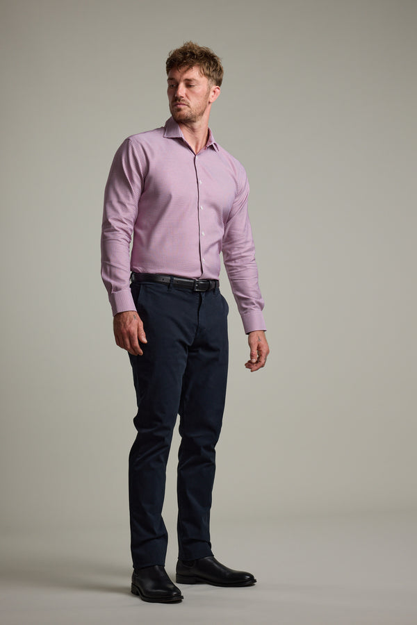 A man stands slightly turned, wearing the Barkers Mitchel Check Business Shirt with dark trousers and black shoes against a plain, light background.