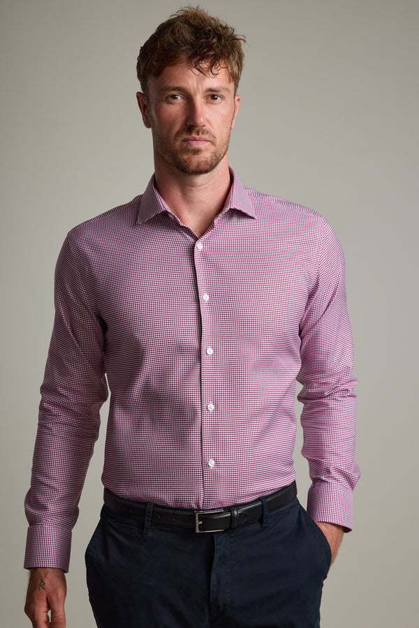 A man with short brown hair and a light beard wears the Barkers Mitchel Check Business Shirt with dark pants, standing against a plain light gray background and displaying a neutral expression.