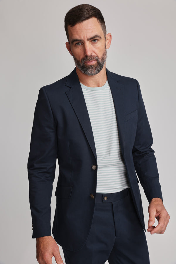 A man with short dark hair and a beard wears the Barkers Maclay Twill Blazer over a light grey and white striped t-shirt, standing against a plain light background and looking directly at the camera with a neutral expression.