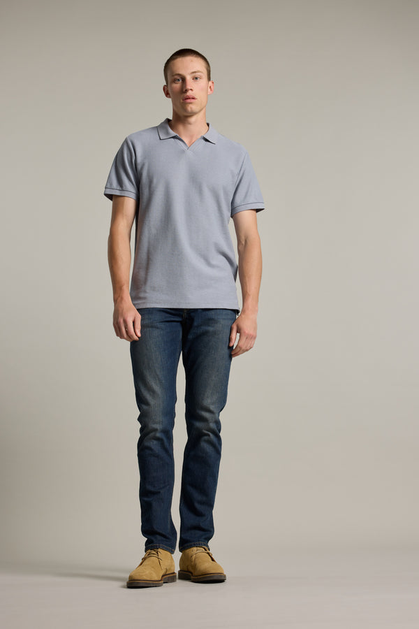 A man in a Barkers Winfield Textured Polo, jeans, and tan shoes stands against a plain background.