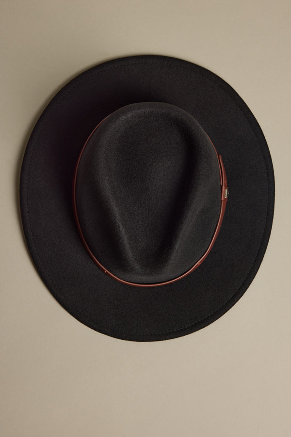 The Brixton Messer Fedora Hat by Brixton, shown from above on a light beige background, features black wool felt with a brown leather band and an adjustable strap.