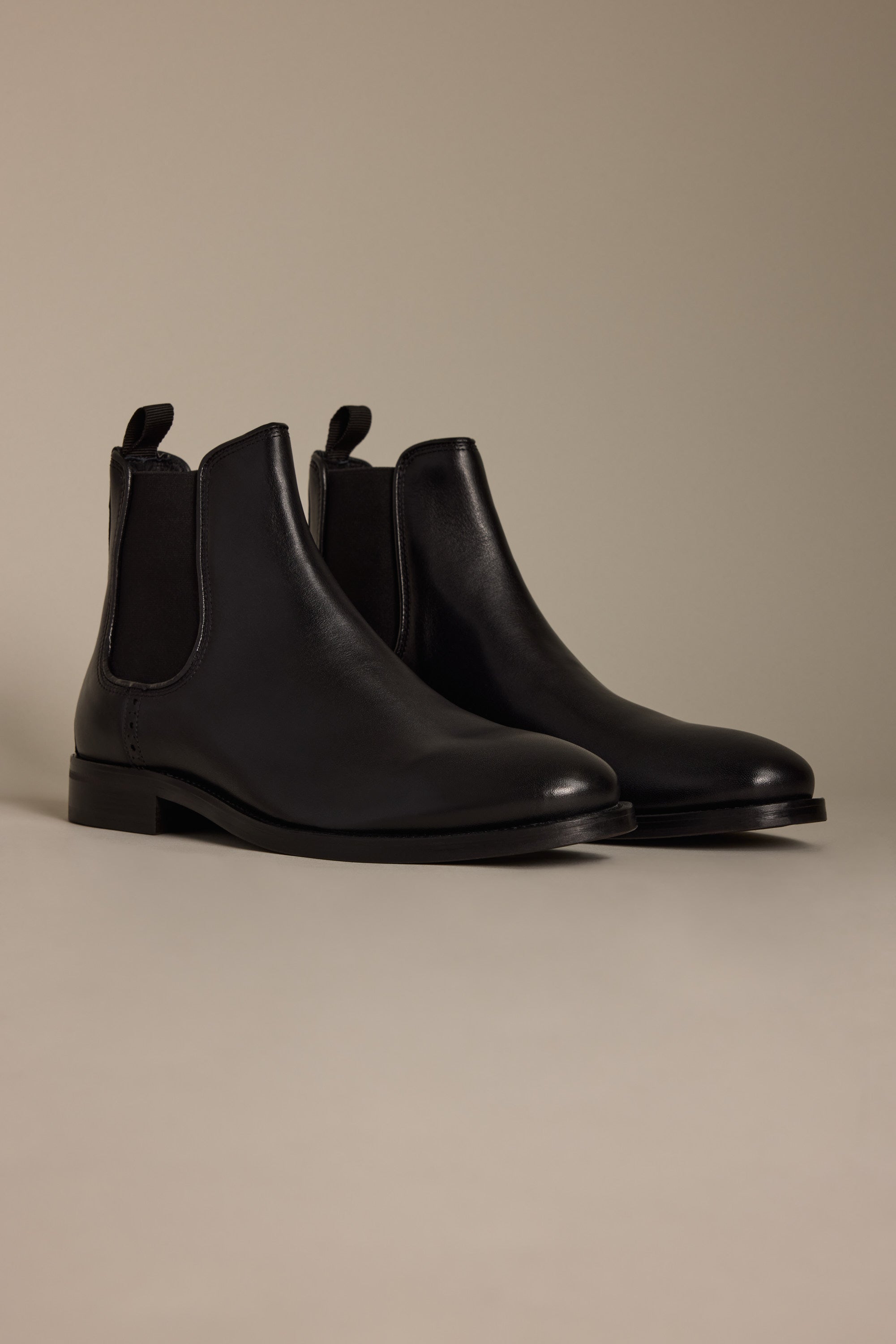 The Peter Chelsea Boot by Barkers, crafted from premium leather with elastic side panels and pull tabs, is showcased on a light beige surface against a matching background.