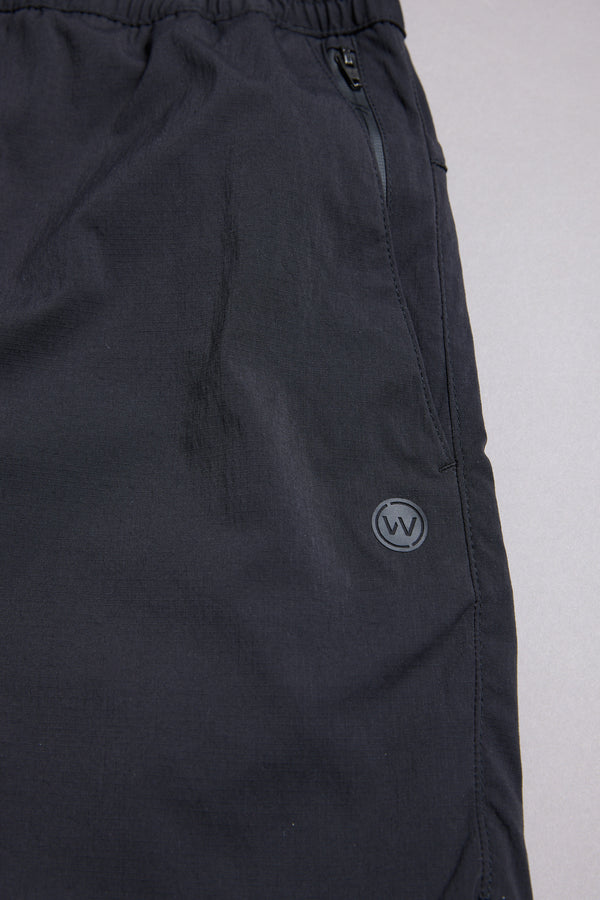 Close-up of the WearEver Agile Short by WearEver, featuring an elastic waistband, zippered side pocket, and small circular W logo on the upper thigh. Made from smooth matte fabric, these lightweight shorts offer all-day comfort with a 7-inch inseam.