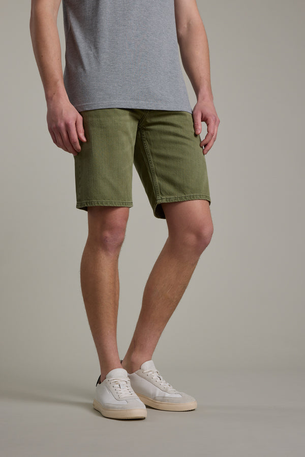 A person wearing a gray t-shirt, Barkers Rover Coloured Denim Short, and white sneakers stands against a plain background, visible from shoulders to feet.