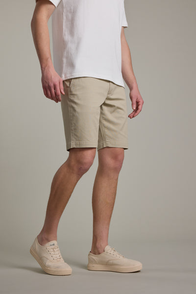 Only the lower body of a person is shown wearing Barkers' Braddock Walk Short, a white t-shirt, and beige sneakers against a plain, light-colored background.