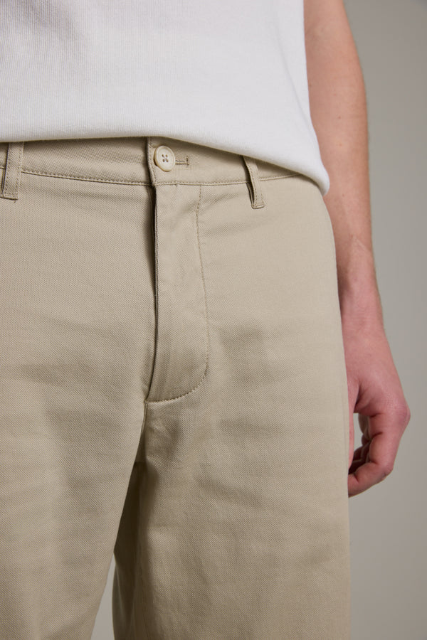 A person wears Barkers Braddock Walk Shorts in beige with a white shirt, shown from waist to mid-thigh, hand resting by their side.
