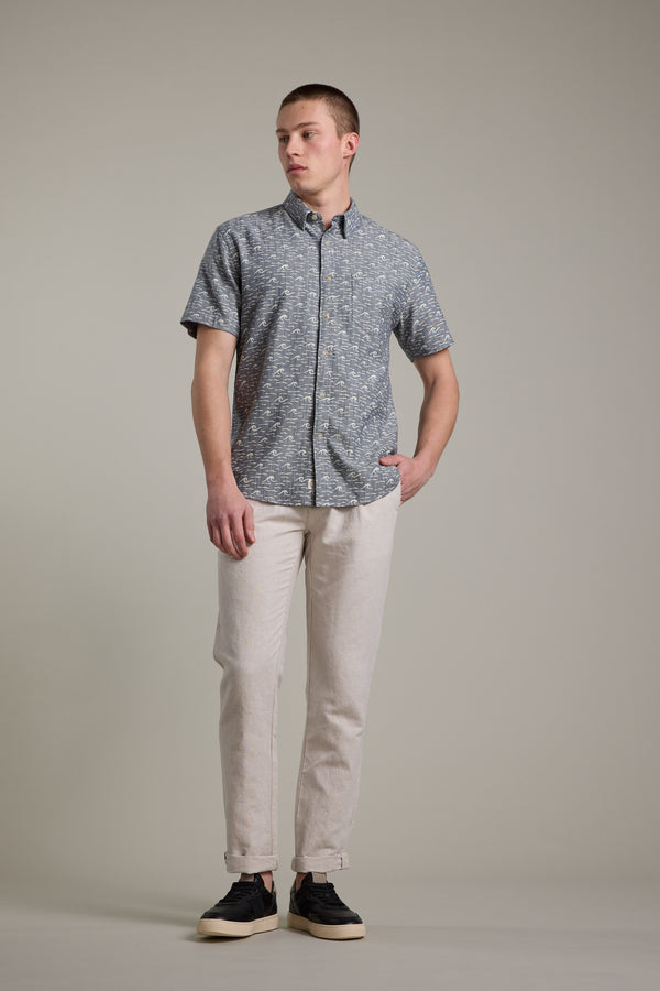 A man stands against a plain background wearing the Barkers Shelby Print Shirt, light beige pants, and black sneakers with white soles. He looks to his left with one hand in his pocket.