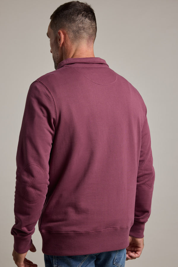 A man is seen from the back in a Barkers Heritage 1/4 Zip sweater by Barkers, paired with blue jeans, standing against a plain light background.