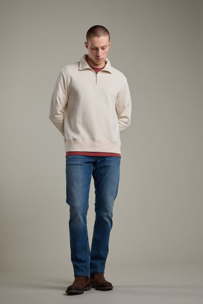 A person faces forward, looking down with hands behind their back. They wear the Barkers Wayfarer 1/4 Zip over a red shirt, blue jeans, and brown shoes, set against a plain neutral background.