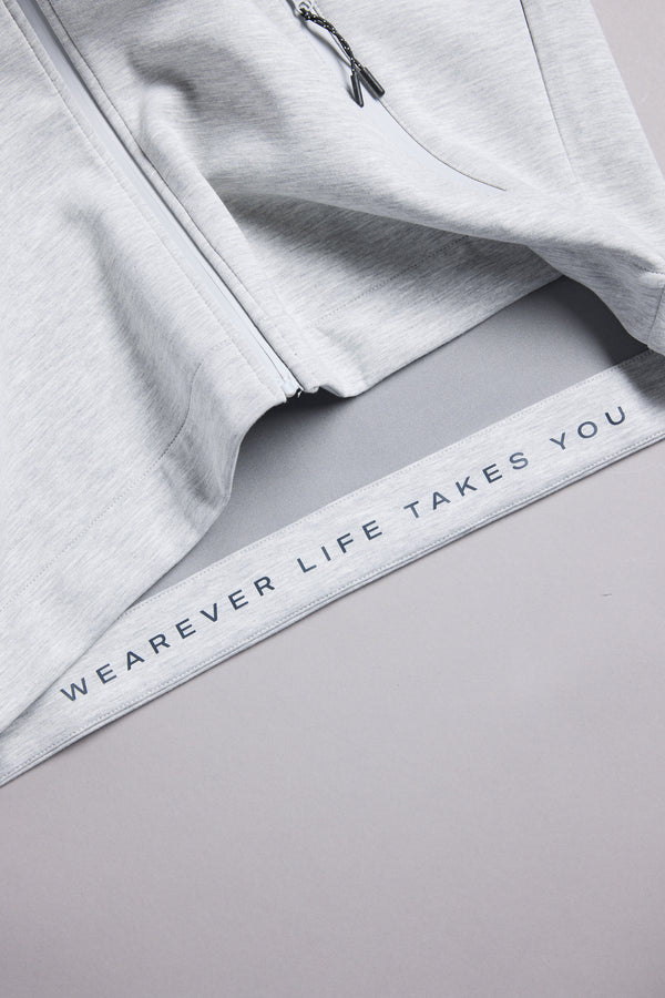 A close-up of the WearEver Altitude Hoody, a light gray tech fleece zip-up by WearEver, featuring "WEAREVER LIFE TAKES YOU" printed along the inner hem.