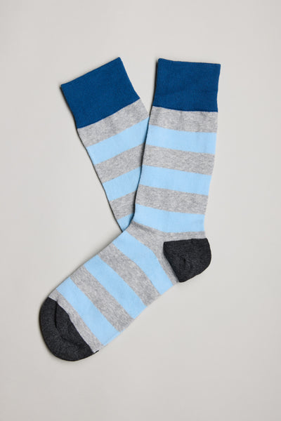 The Barkers Brodie Stripe Sock is a comfortable cotton sock with wide light blue and gray stripes, dark blue cuffs, and dark gray heels and toes, shown on a neutral background.