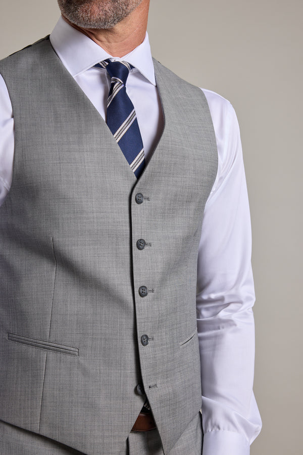 A man models the Barkers Henry Waistcoat in light grey over a white dress shirt with a navy and white striped tie; only his lower face and torso are visible.