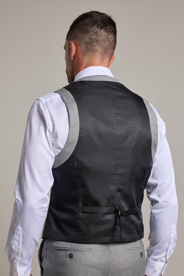 A man is shown from the back wearing the Barkers Henry Waistcoat, part of a premium wool three-piece suit. The vest features a black satin back with a subtle checkered pattern and an adjustable waist strap.