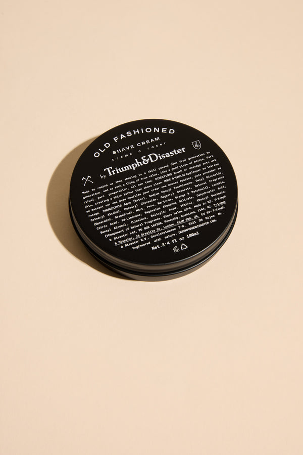 Triumph & Disaster Old Fashioned Shave Cream Jar in black tin on beige background.