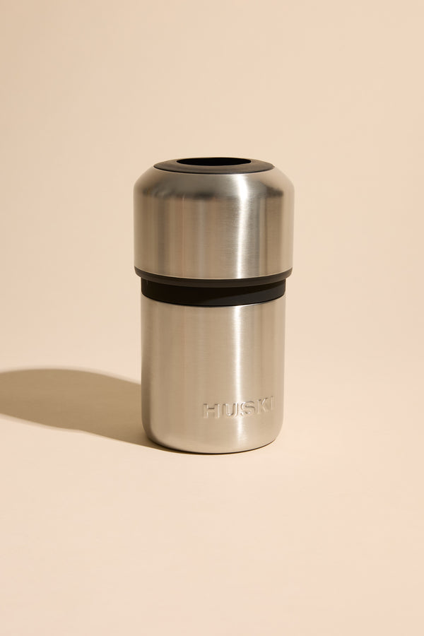 Huski Wine Cooler and stainless steel cup with Huski logo on a beige background.