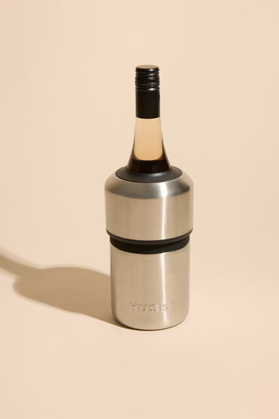 A Huski Wine Cooler by Huski holds a wine bottle elegantly on a beige surface.