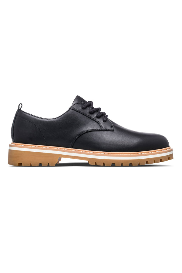 The CLAE Logan by Clae is a black leather lace-up oxford with a tan rubber sole, visible stitching, and a recycled PU foam insole, shown in side profile on a white background.