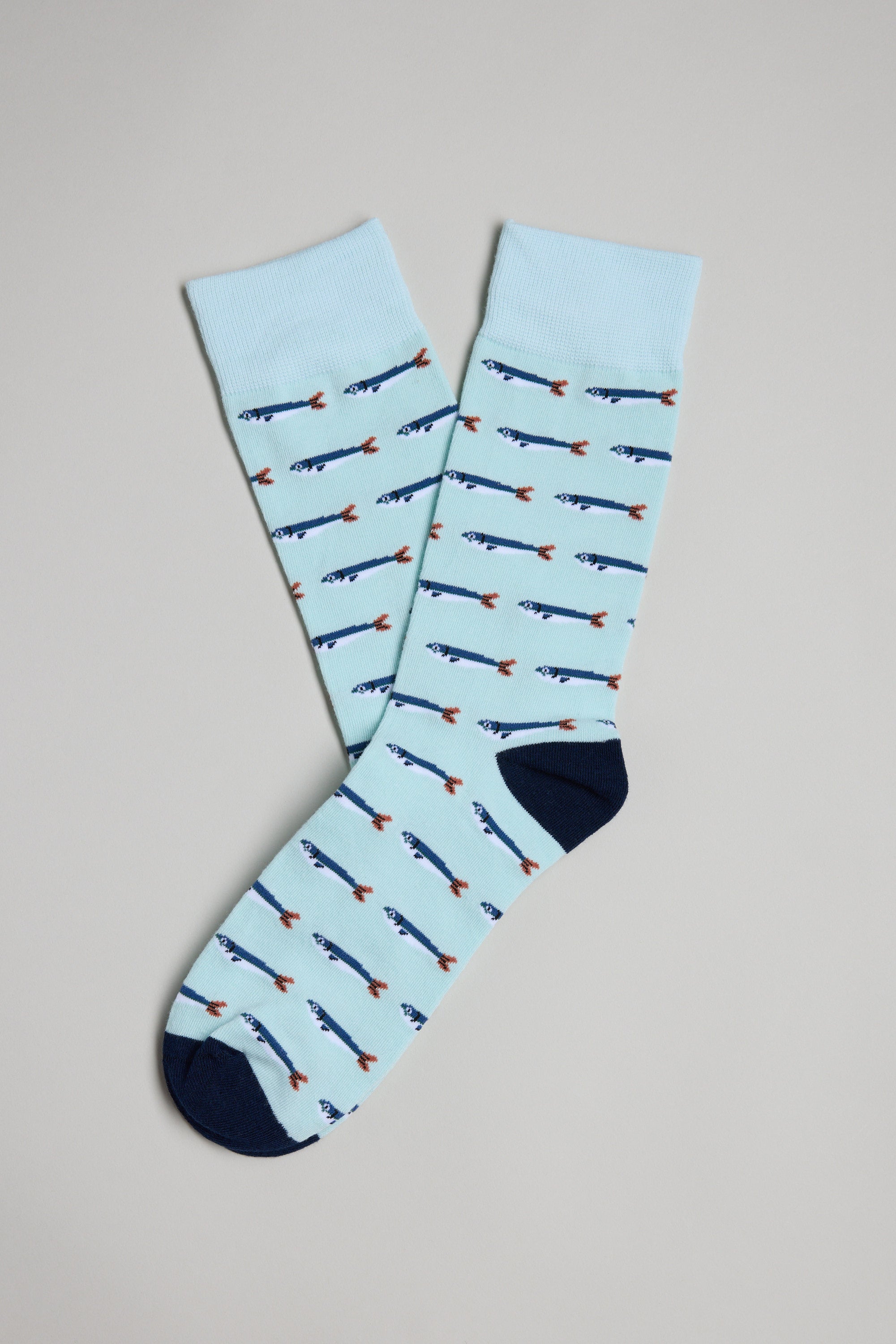 Barkers Sardine Sock in light blue cotton with small fish pattern and dark blue toes and heels, shown flat on a light gray background—a playful men’s gift.