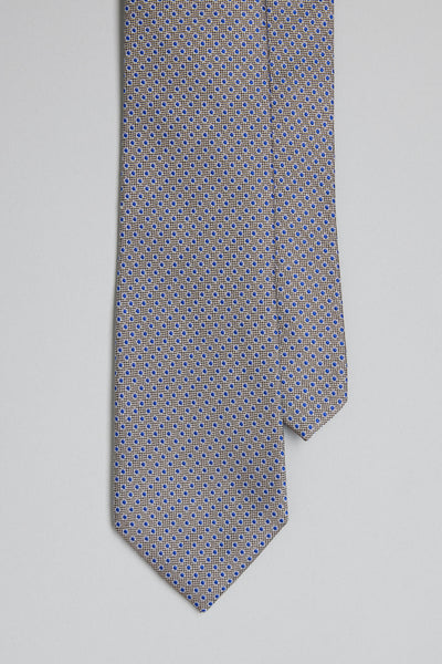 The Barkers Waller Dot Tie features a close-up of its silk fabric, adorned with a small blue and yellow jacquard geometric print on a light gray background, displayed on a plain white surface.