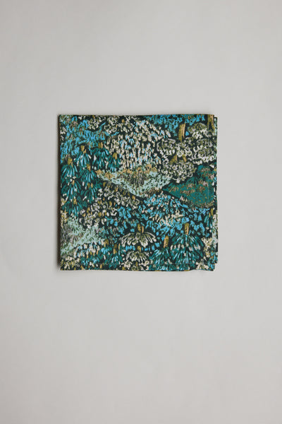 The Liberty Darley Hillside PS by Liberty is a folded rectangular pocket square in Tana Lawn cotton, showcasing a dense abstract bush print in green, blue, black, and white on a plain white background.