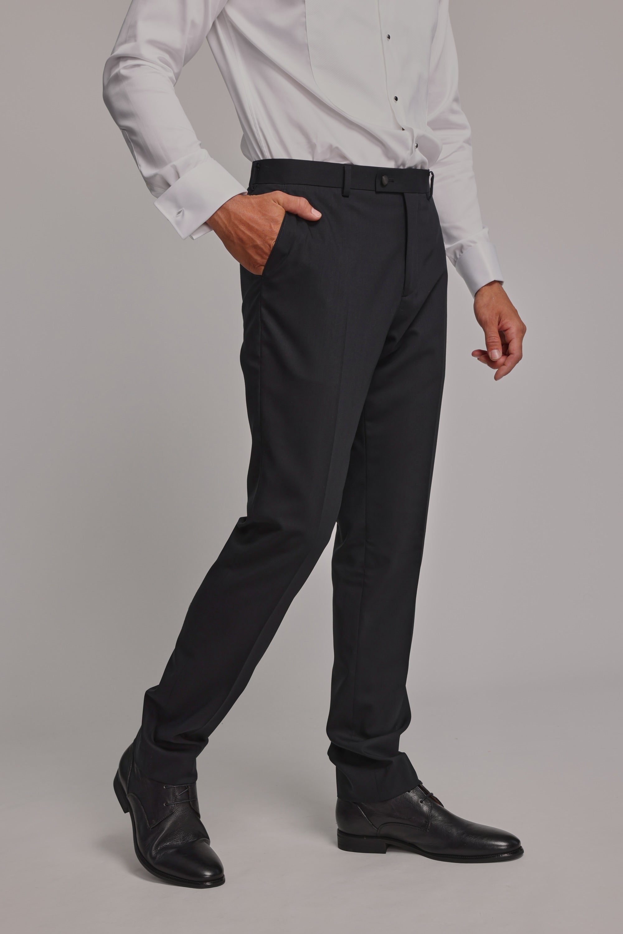 A man wearing a white dress shirt and Barkers Princeton Texture Trouser in black, along with black dress shoes, stands with one hand in his pocket against a plain background. His head is not visible in the image.