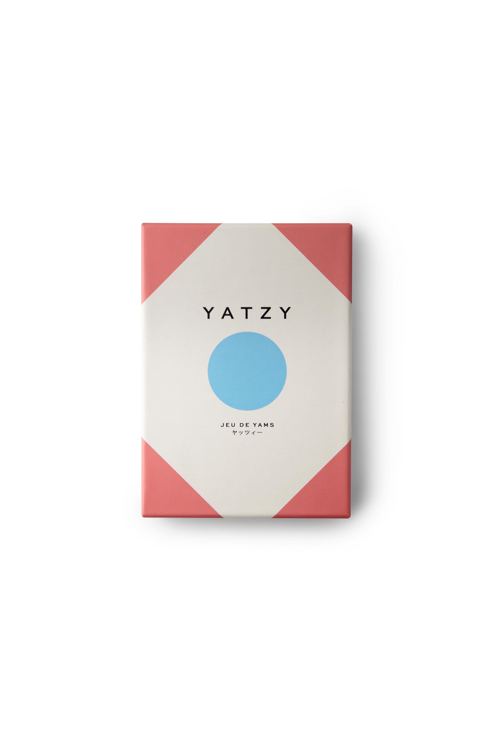 The Classic Yatzy Game by Printworks features minimalist boxed packaging with a large blue circle, pink corners, and black “Yatzy” and “Jeu de Yams” text on white—a perfect classic dice game for family board game nights.