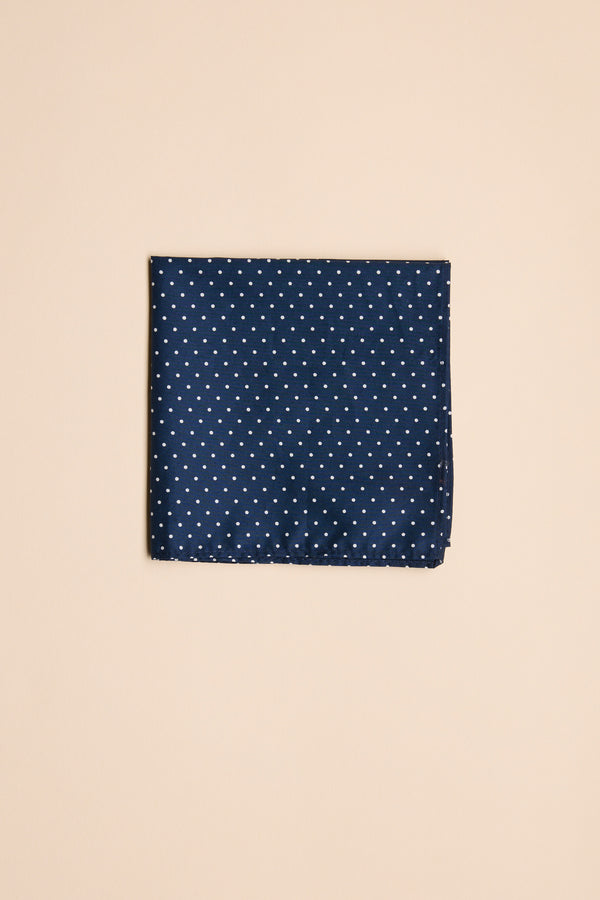 The Barkers Polka Dot Pocket Square is a finely crafted navy cotton accessory with small white polka dots, shown here neatly folded against a plain beige background.