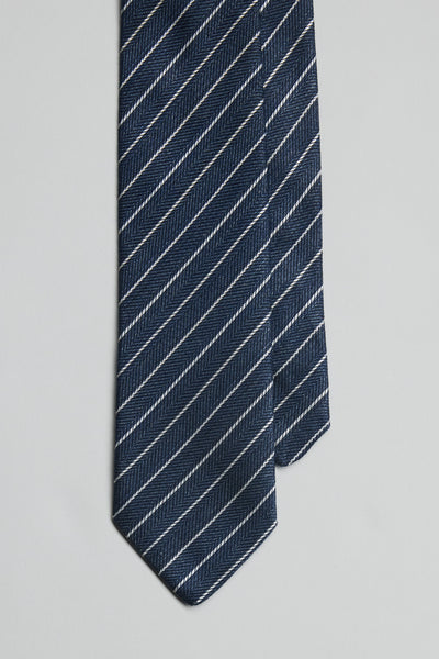 A close-up of the Parisian Lanark Stripe Tie by Parisian, featuring dark blue fabric with diagonal white stripes, set against a light gray background.