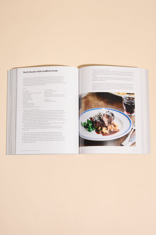 An open Eat Up New Zealand The Bach Edition cookbook by Other shows a recipe and a photo of plated beef with greens and brown sauce on a beige surface—ideal for exploring seasonal New Zealand recipes.